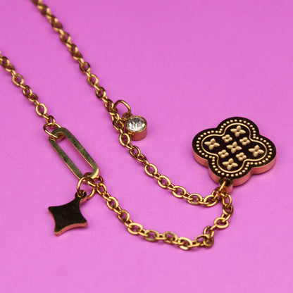 Gold necklace with charms on a pink background