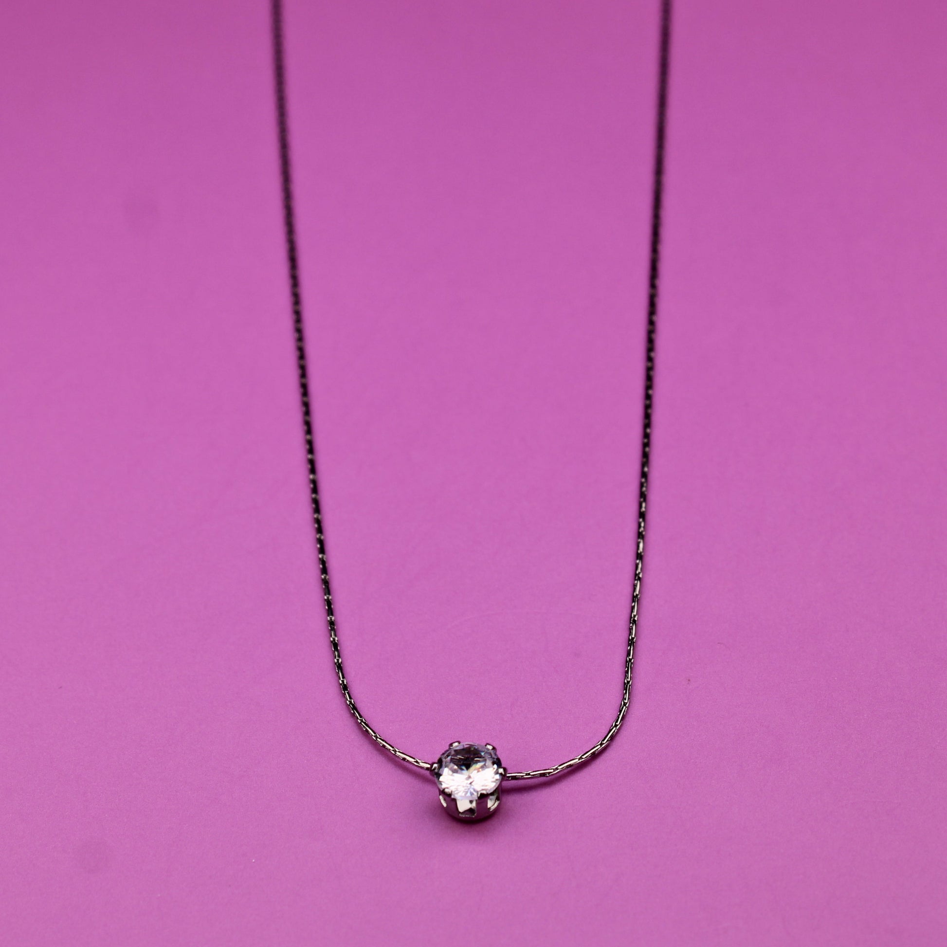 Necklace with a small round pendant on a pink background