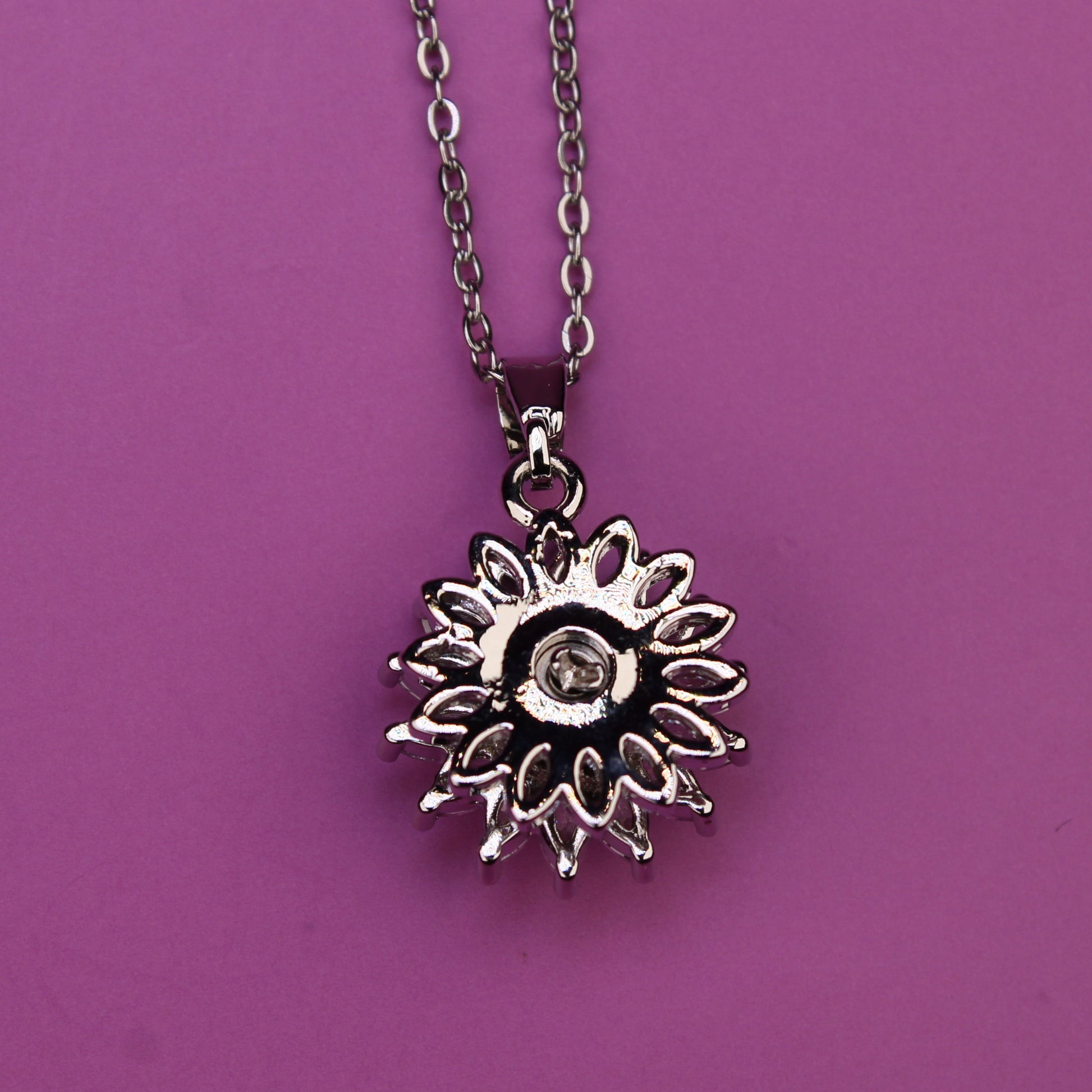 Silver sunflower pendant necklace on a purple background