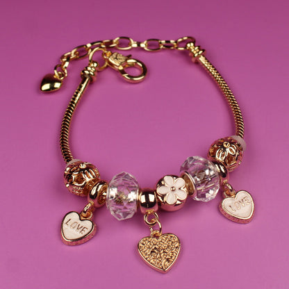 Gold bracelet with heart-shaped charms on a pink background