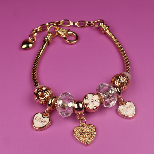 Gold bracelet with heart-shaped charms on a pink background