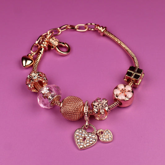 Gold bracelet with charms on a pink background