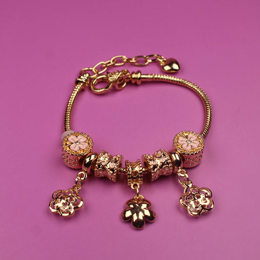 Gold bracelet with charms on a pink background