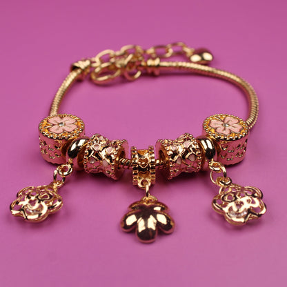 Gold bracelet with charms on a pink background