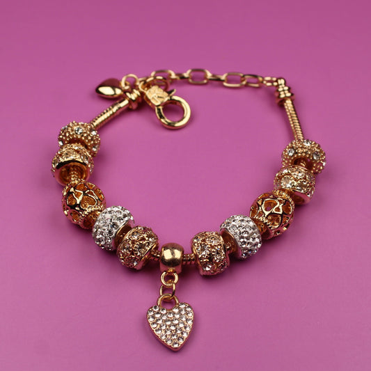 Gold bracelet with heart charm on a pink background