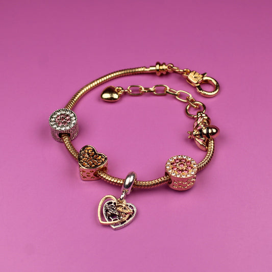 Gold bracelet with charms on a pink background