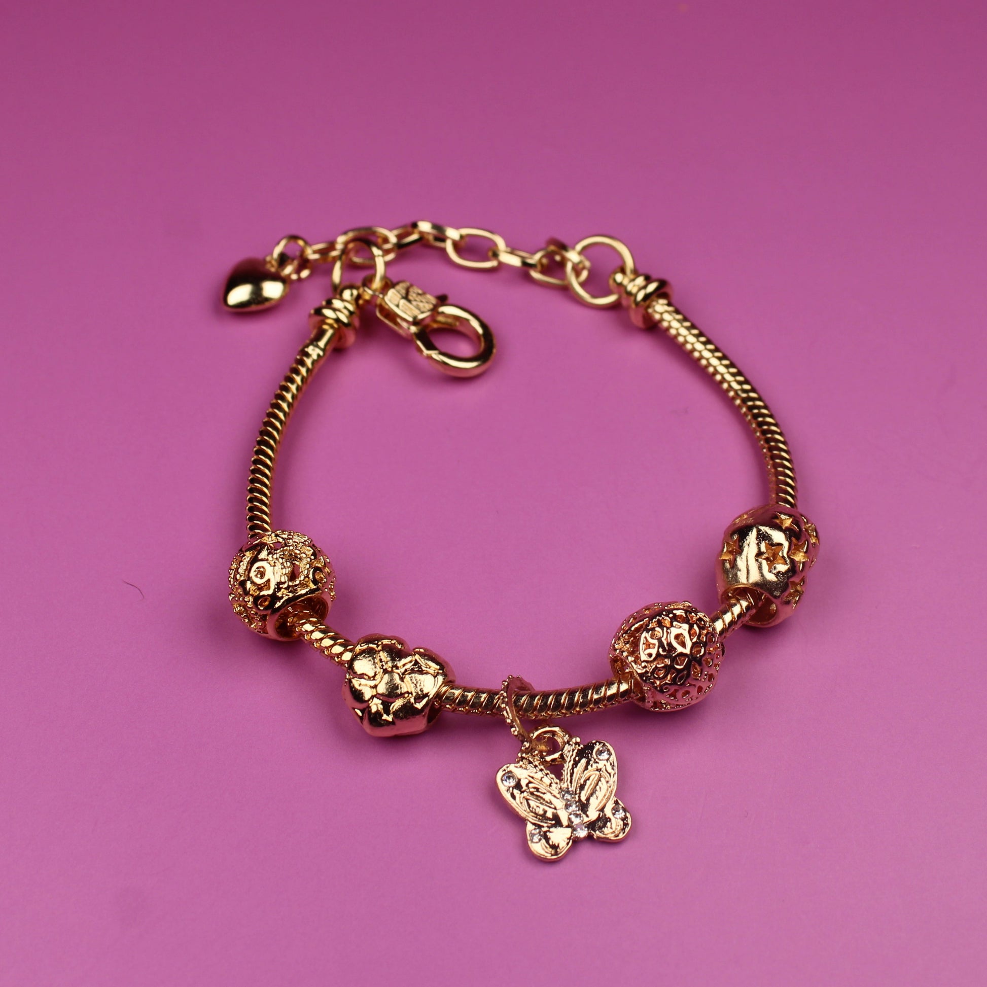 Gold bracelet with charms on a pink background
