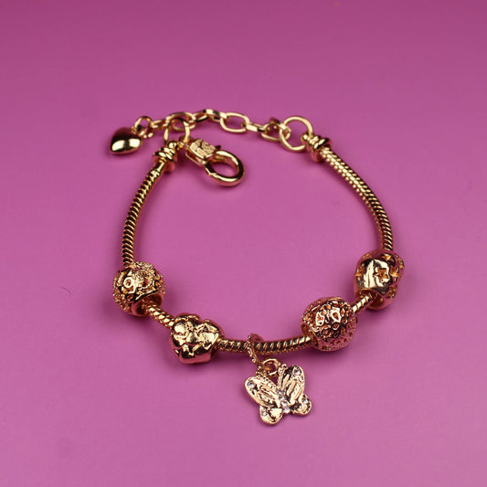 Gold bracelet with charms on a pink background