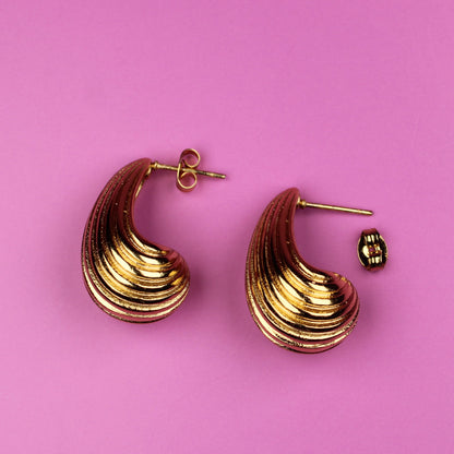 Gold hoop earrings on a pink background