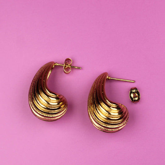 Gold hoop earrings on a pink background