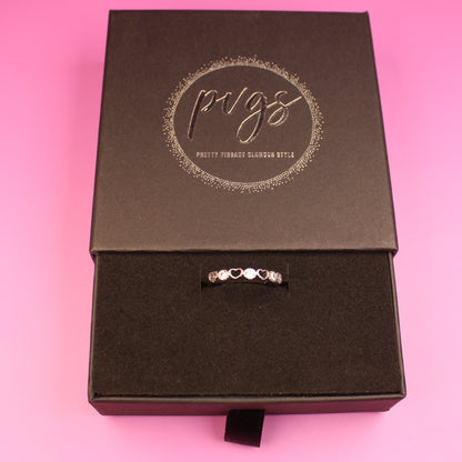 Black jewelry box with a ring on a pink background