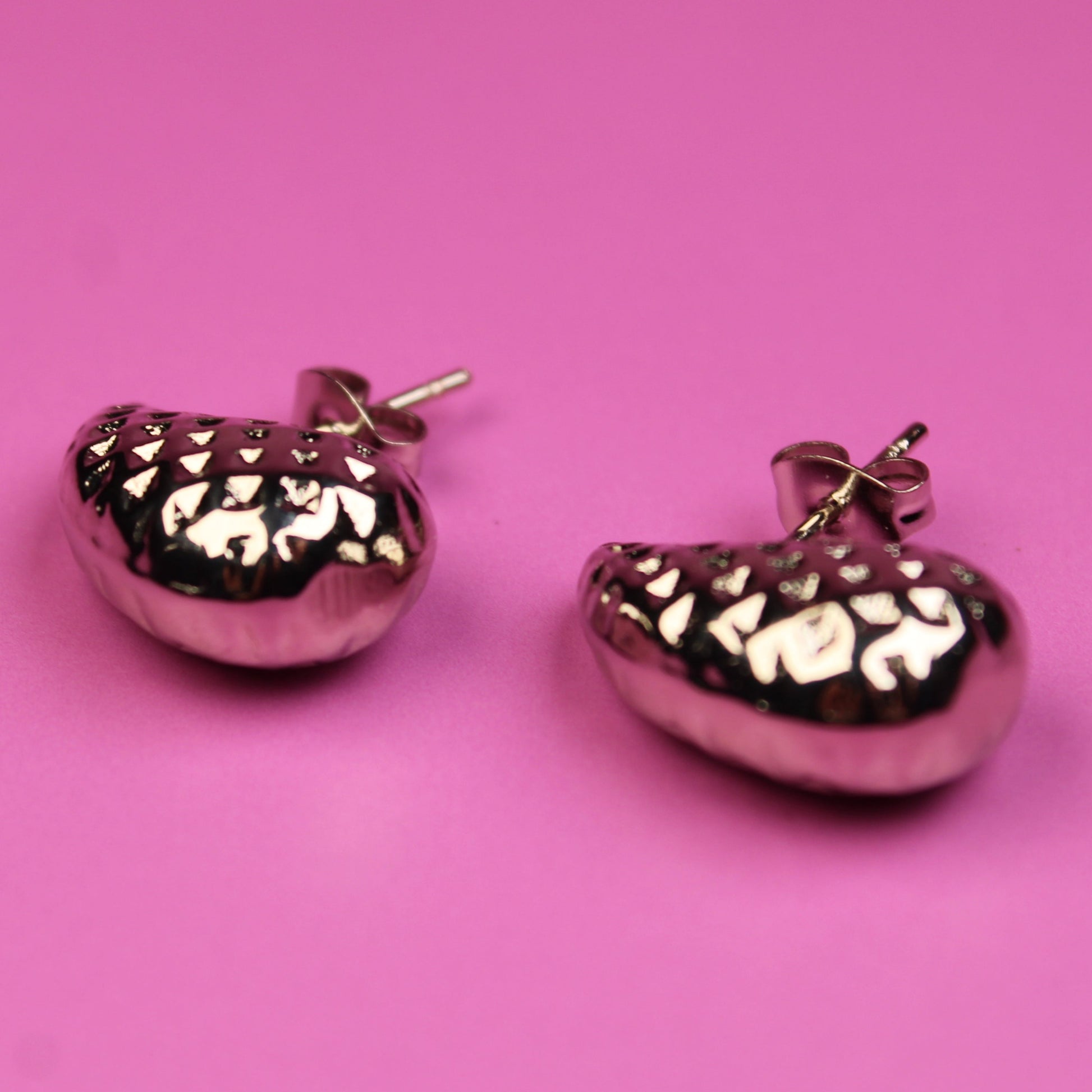 Pink heart-shaped earrings on a pink background