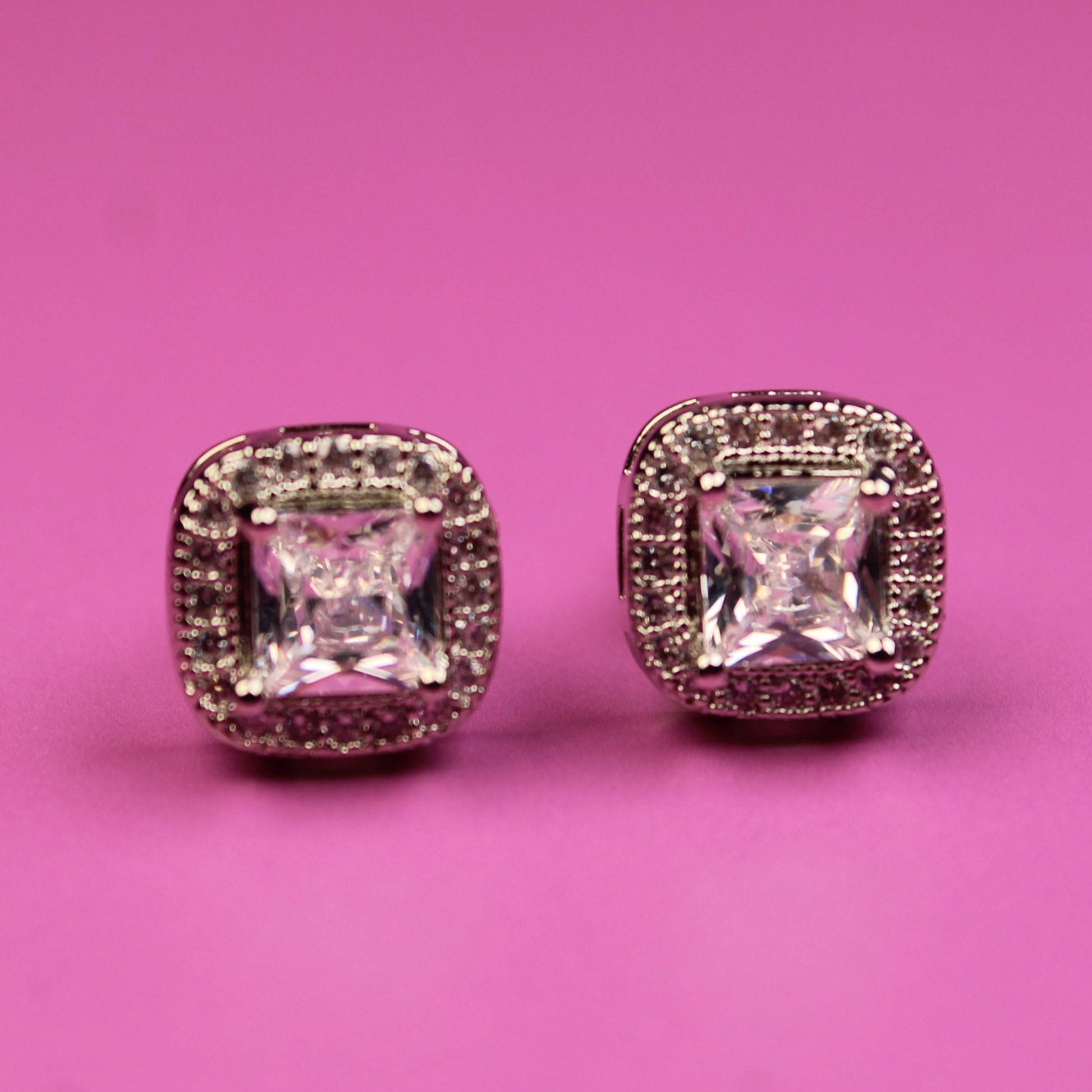 Pair of diamond earrings on a pink background