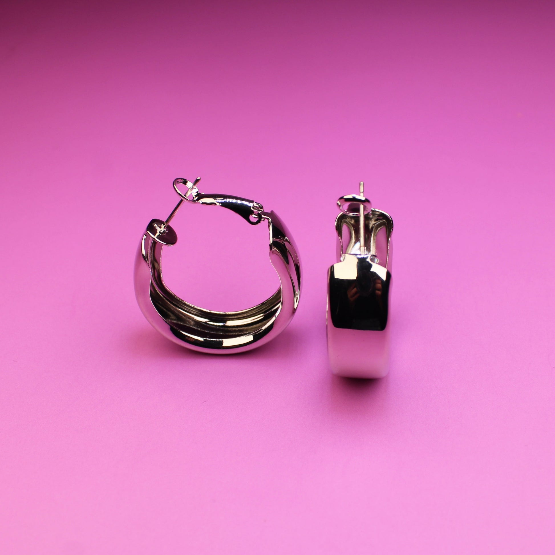 Silver hoop earrings on a pink background