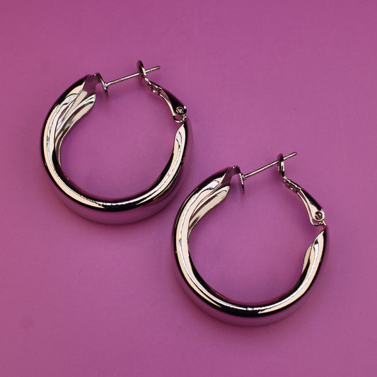 Silver hoop earrings on a pink background