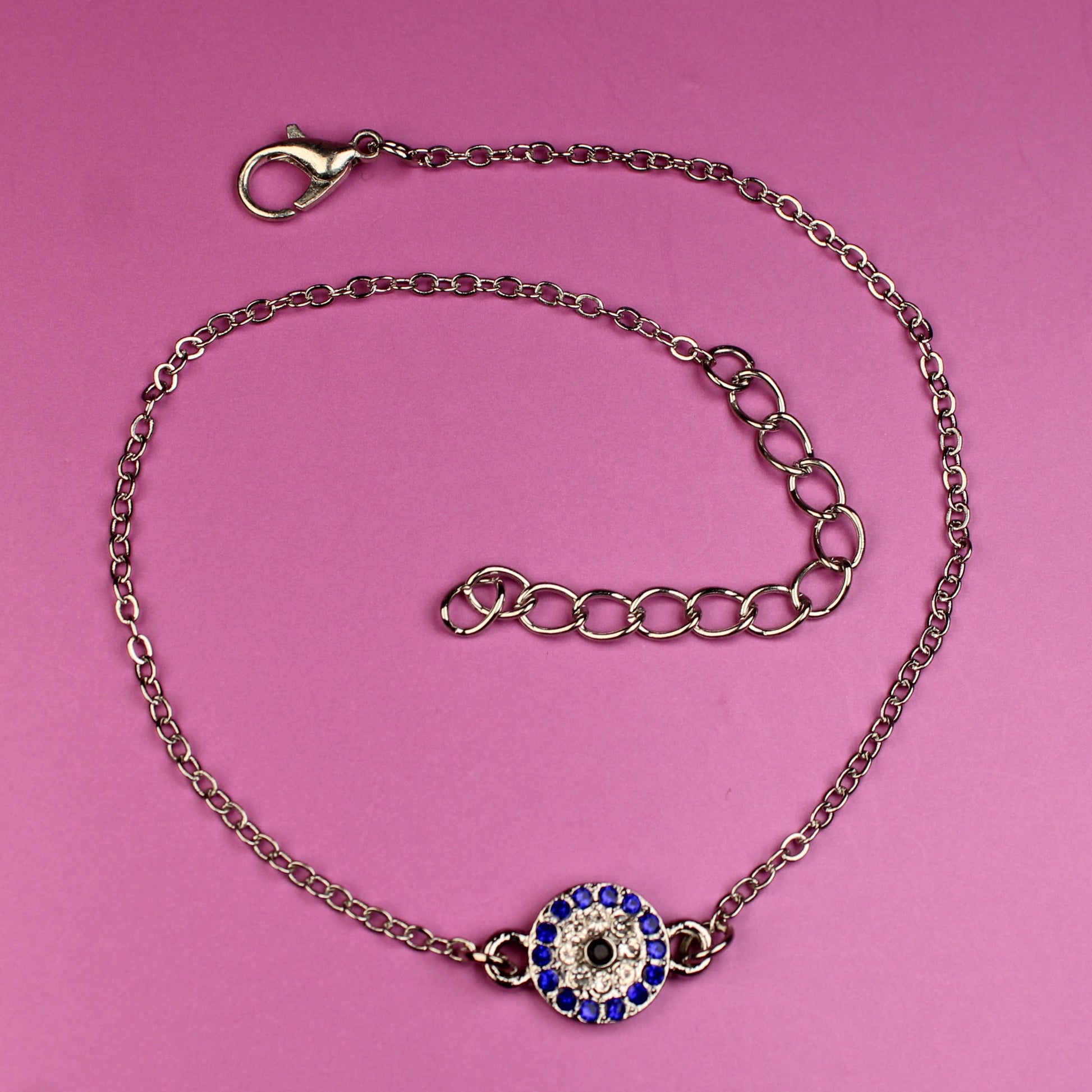 Bracelet with a blue and purple evil eye charm on a pink background