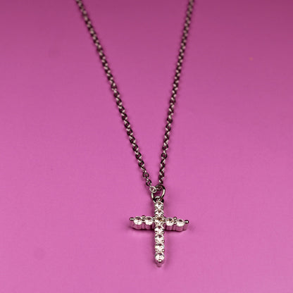 Necklace with a cross pendant on a pink background