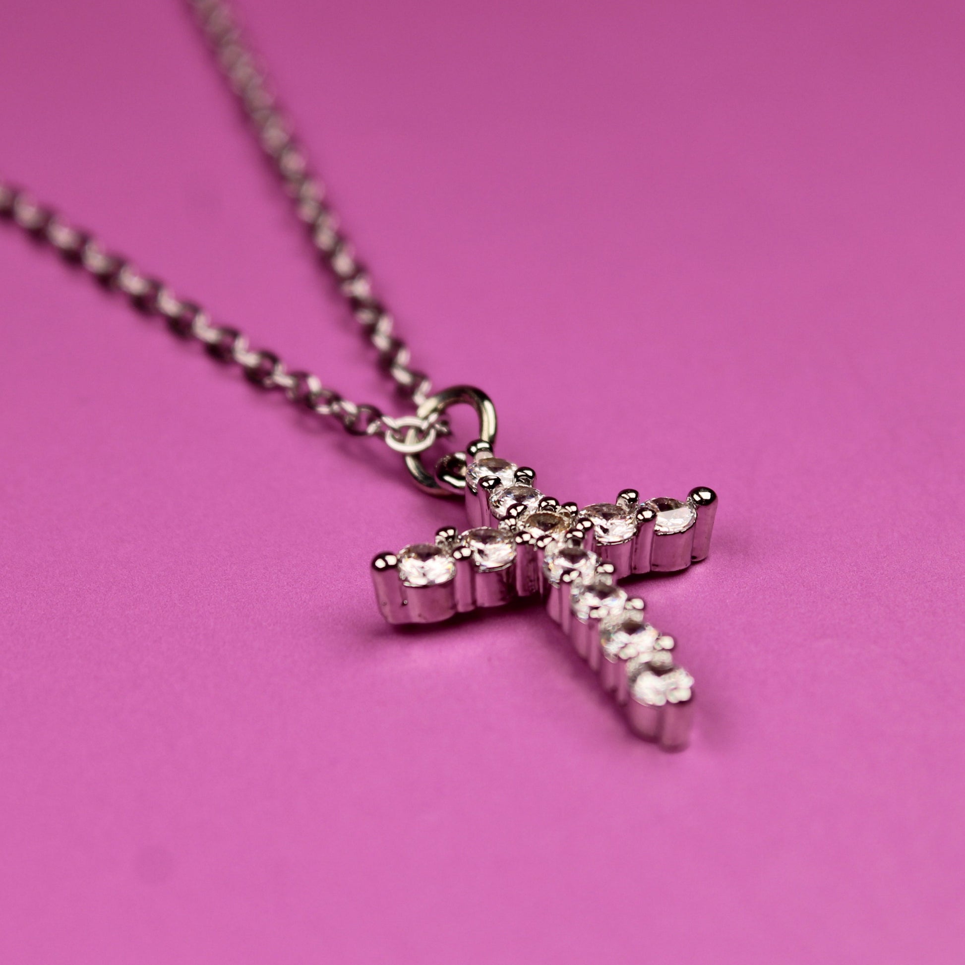 Pink cross necklace on a pink background