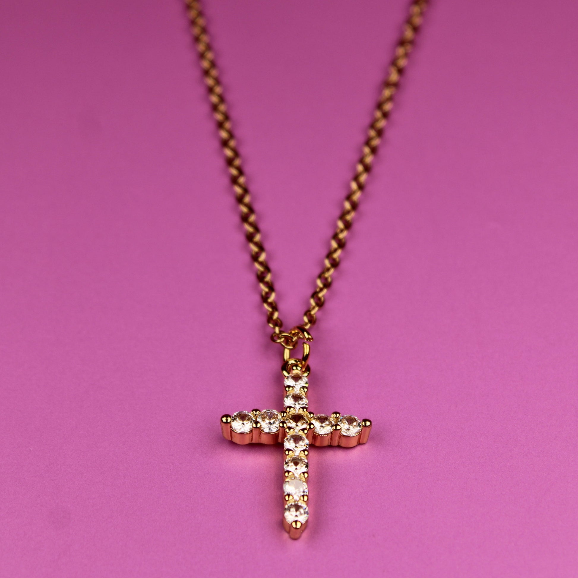 Necklace with a cross pendant on a pink background