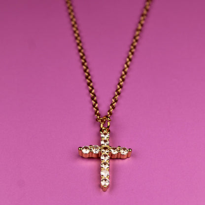 Necklace with a cross pendant on a pink background