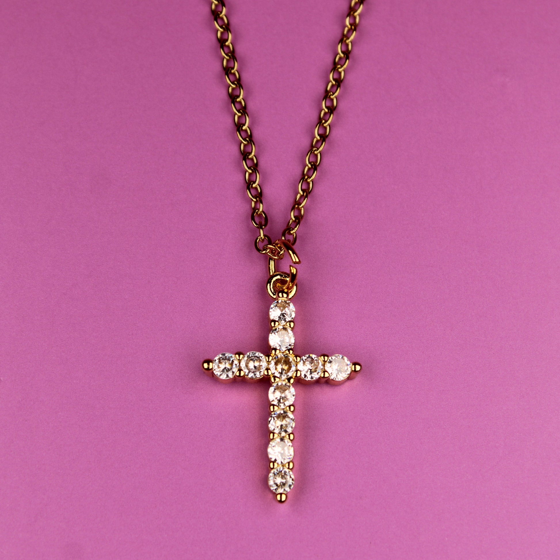 Cross necklace with diamonds on a pink background