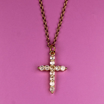 Cross necklace with diamonds on a pink background