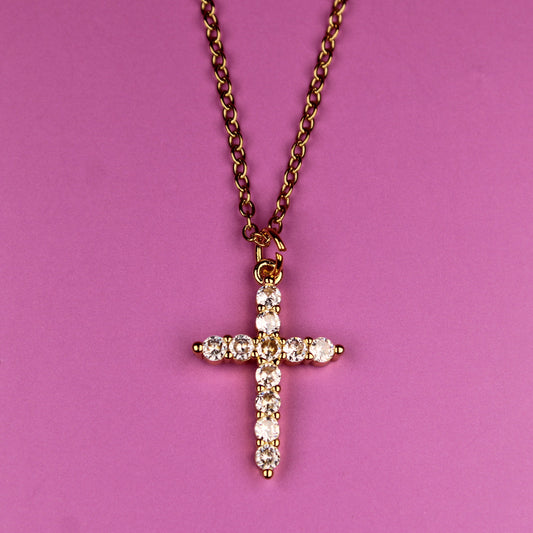 Cross necklace with diamonds on a pink background