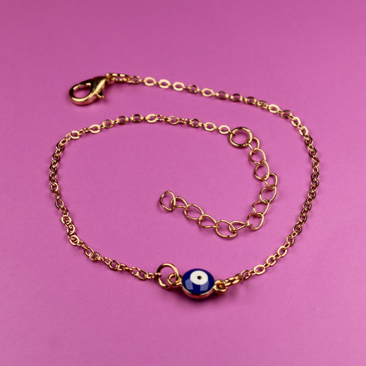 Gold bracelet with a blue charm on a pink background