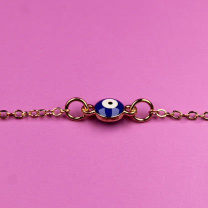 Bracelet with a blue evil eye charm on a pink background