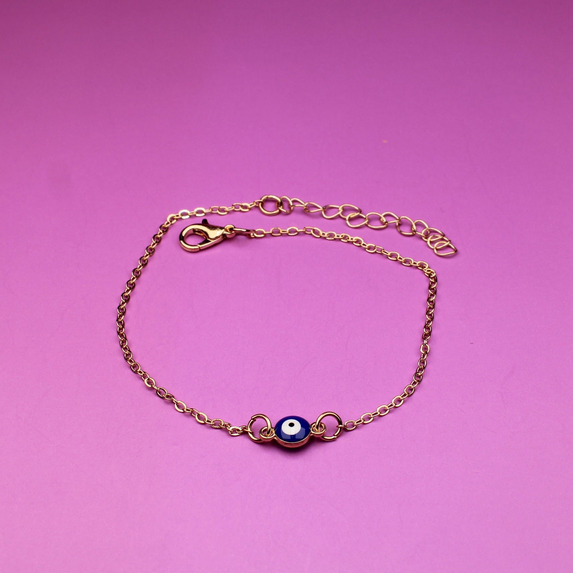 Gold bracelet with a purple gemstone on a pink background