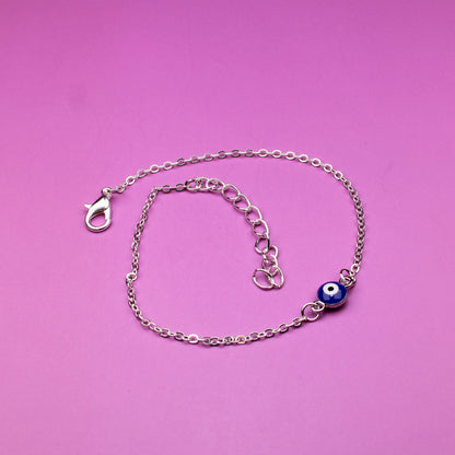Silver bracelet with a blue evil eye charm on a pink background