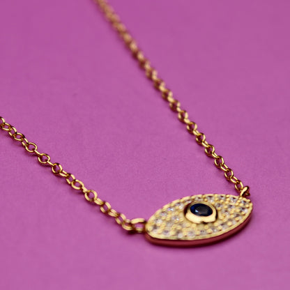 Gold necklace with an eye-shaped pendant on a purple background