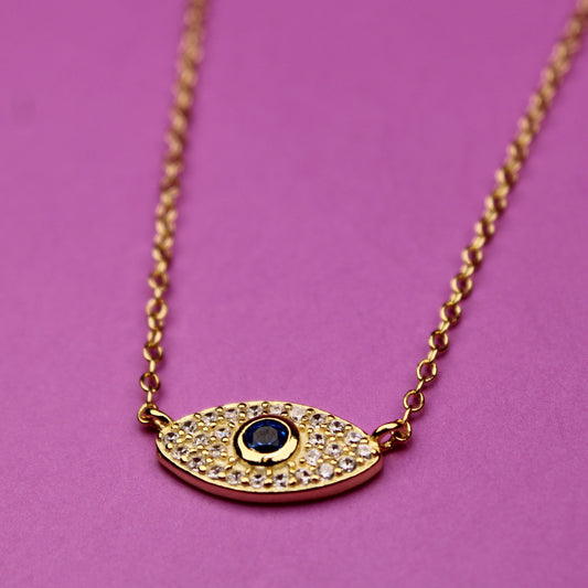 Gold necklace with an eye-shaped pendant on a pink background