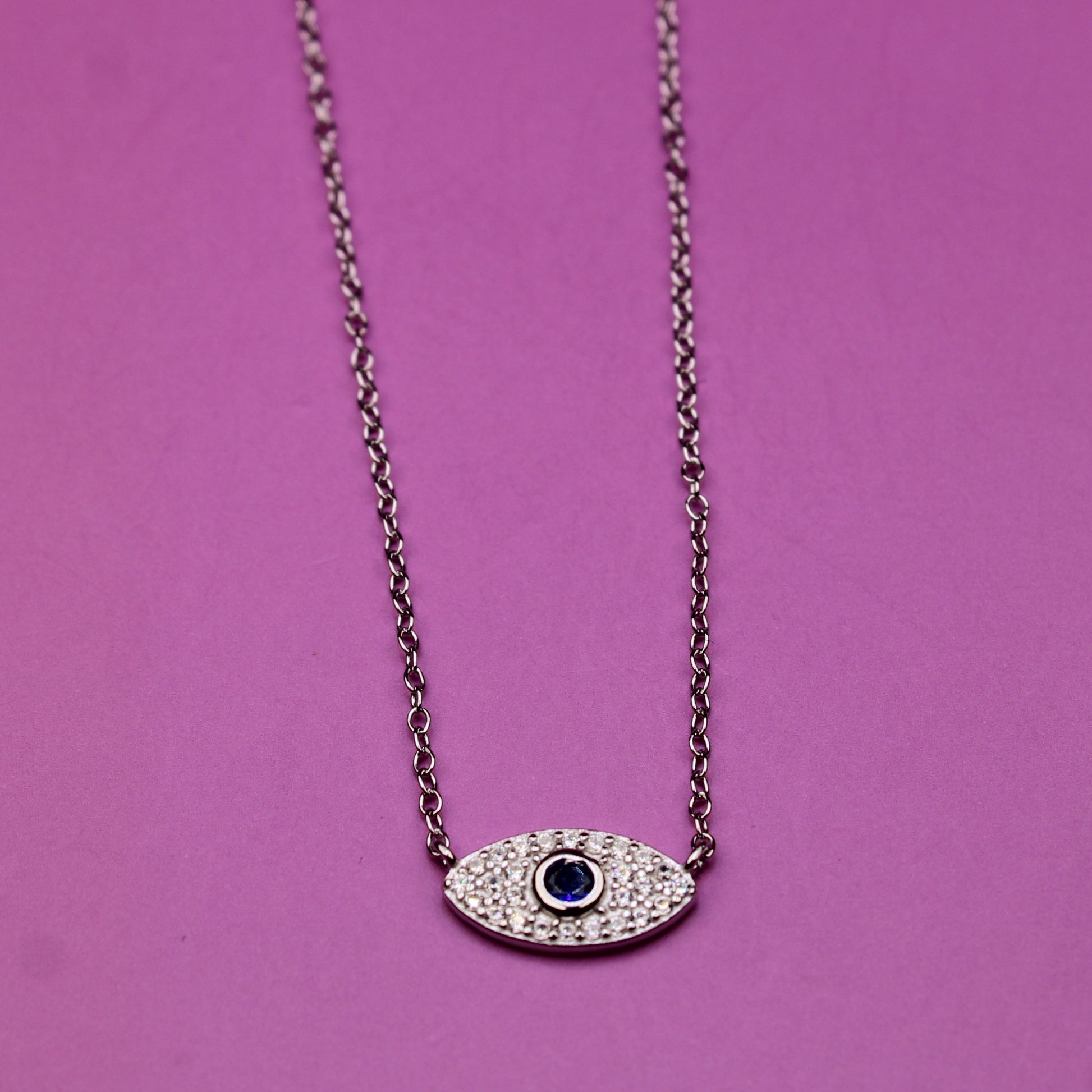 Necklace with an eye-shaped pendant on a pink background