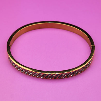 Gold bracelet with red stones on a pink background