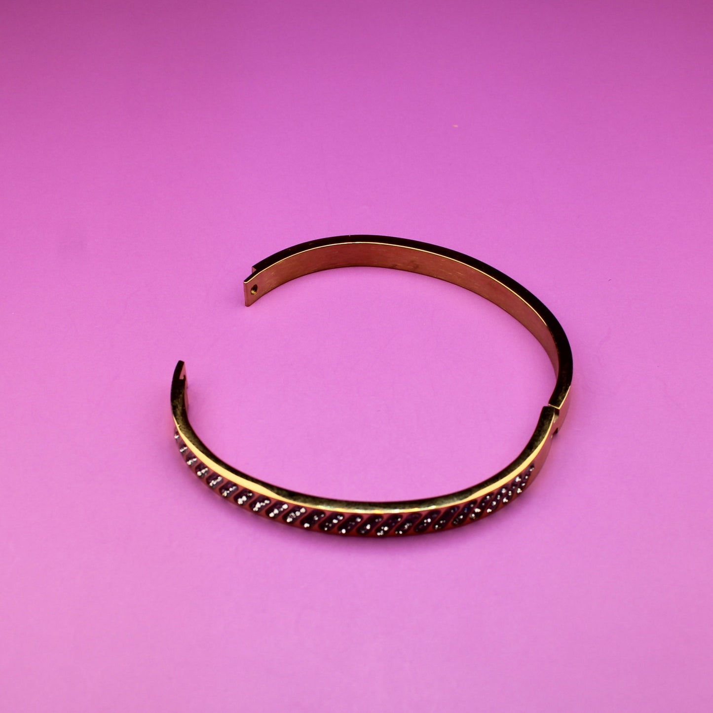 Gold bracelet on a pink background