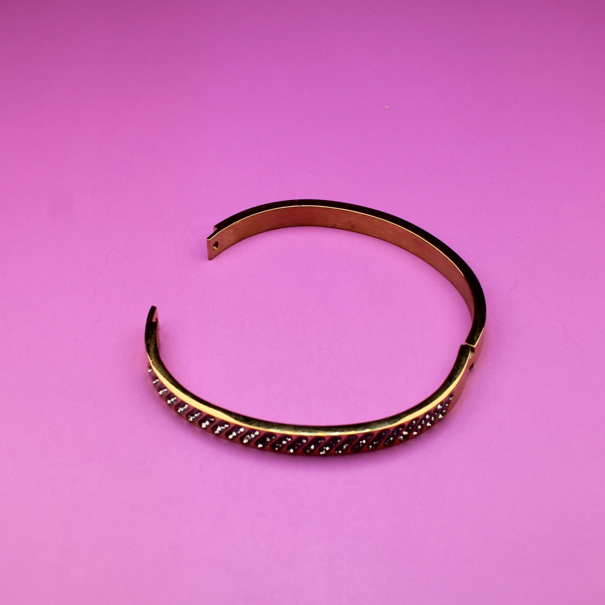 Gold bracelet on a pink background