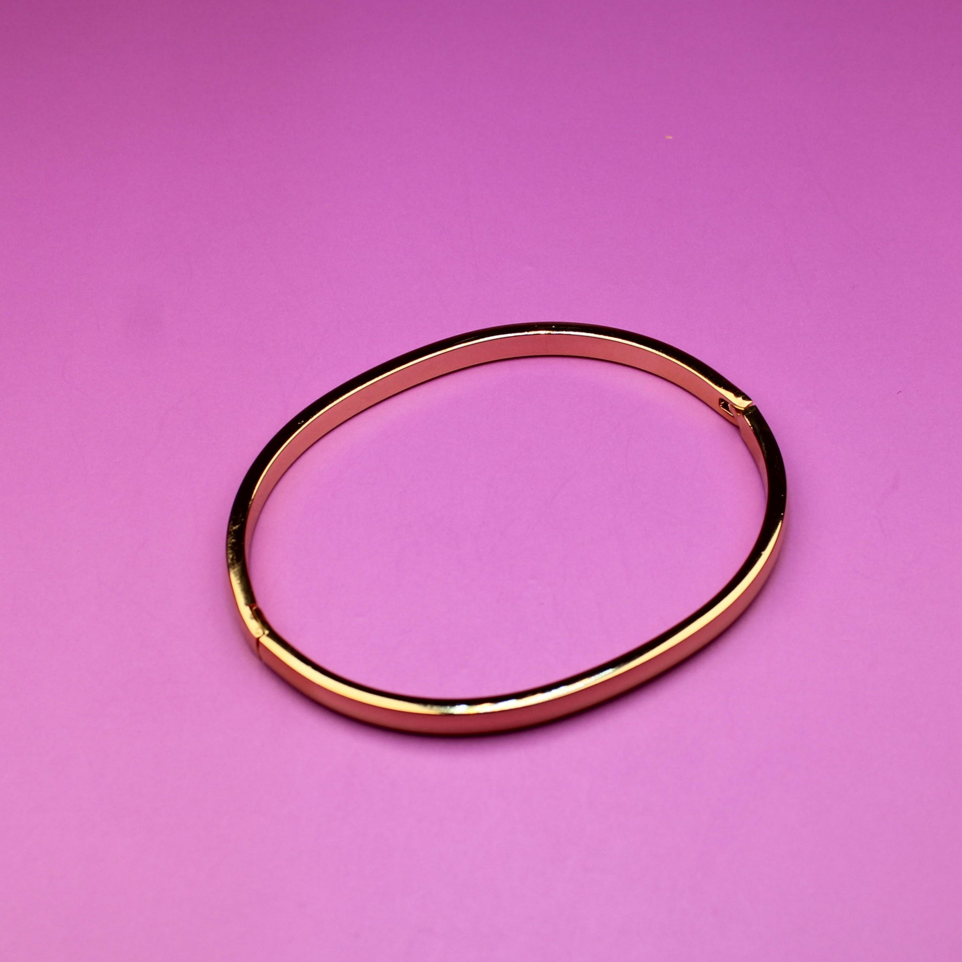 Gold bracelet on a pink background