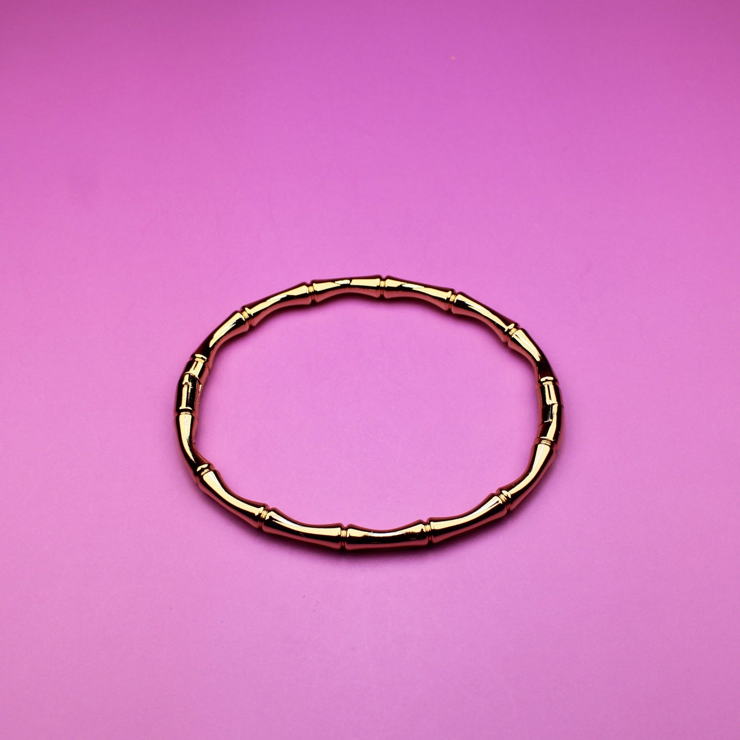 Gold bracelet on a pink background