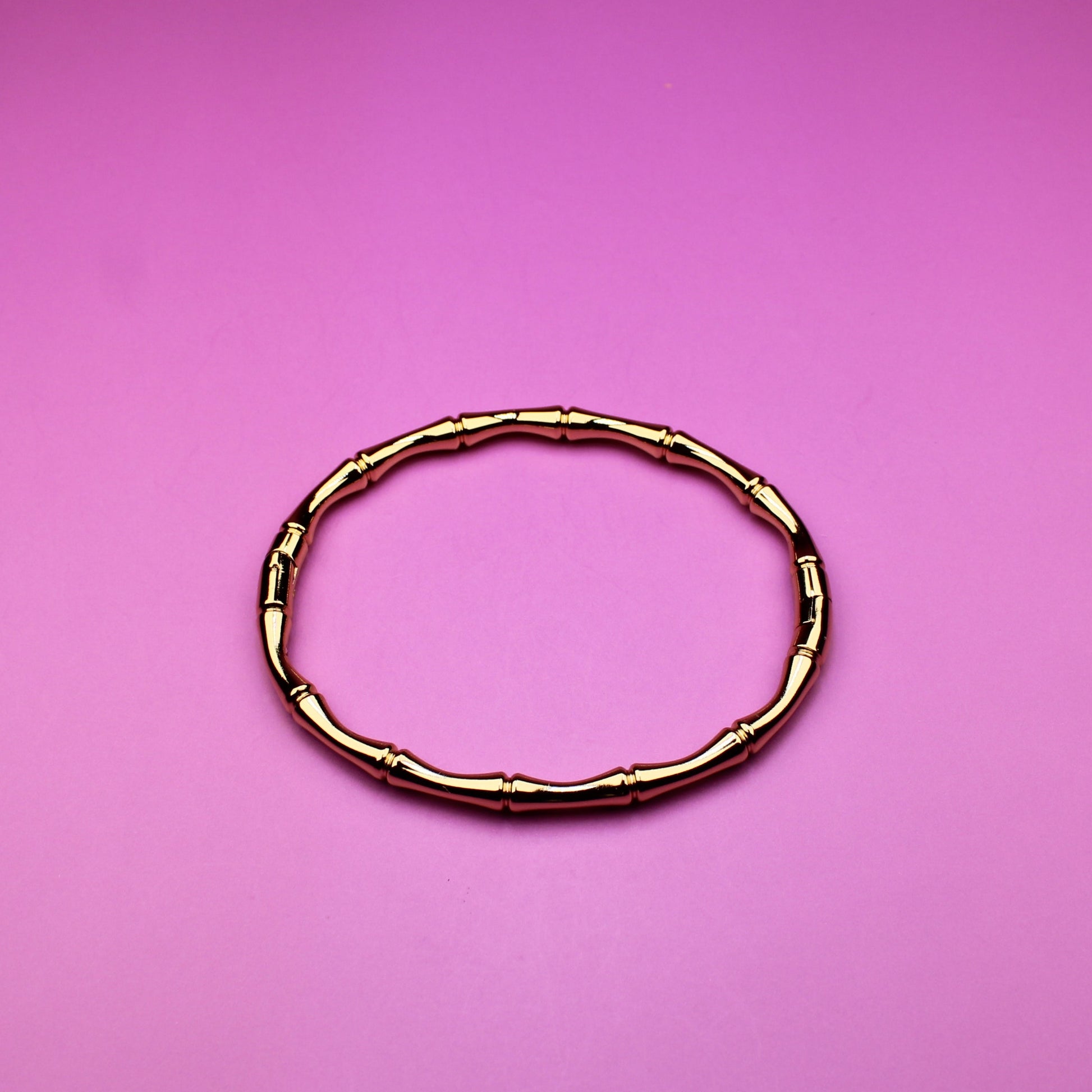 Gold bracelet on a pink background