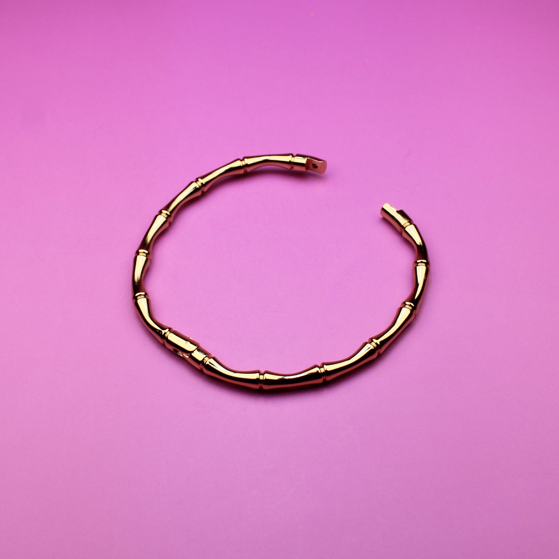 Gold bracelet on a pink background
