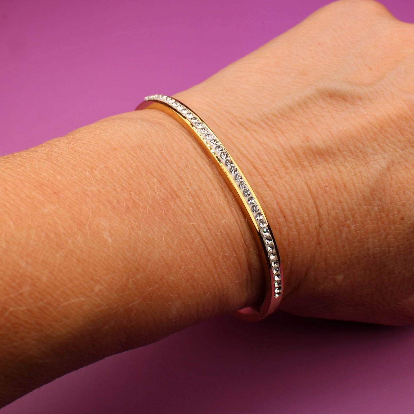 Hand wearing a bracelet on a purple background