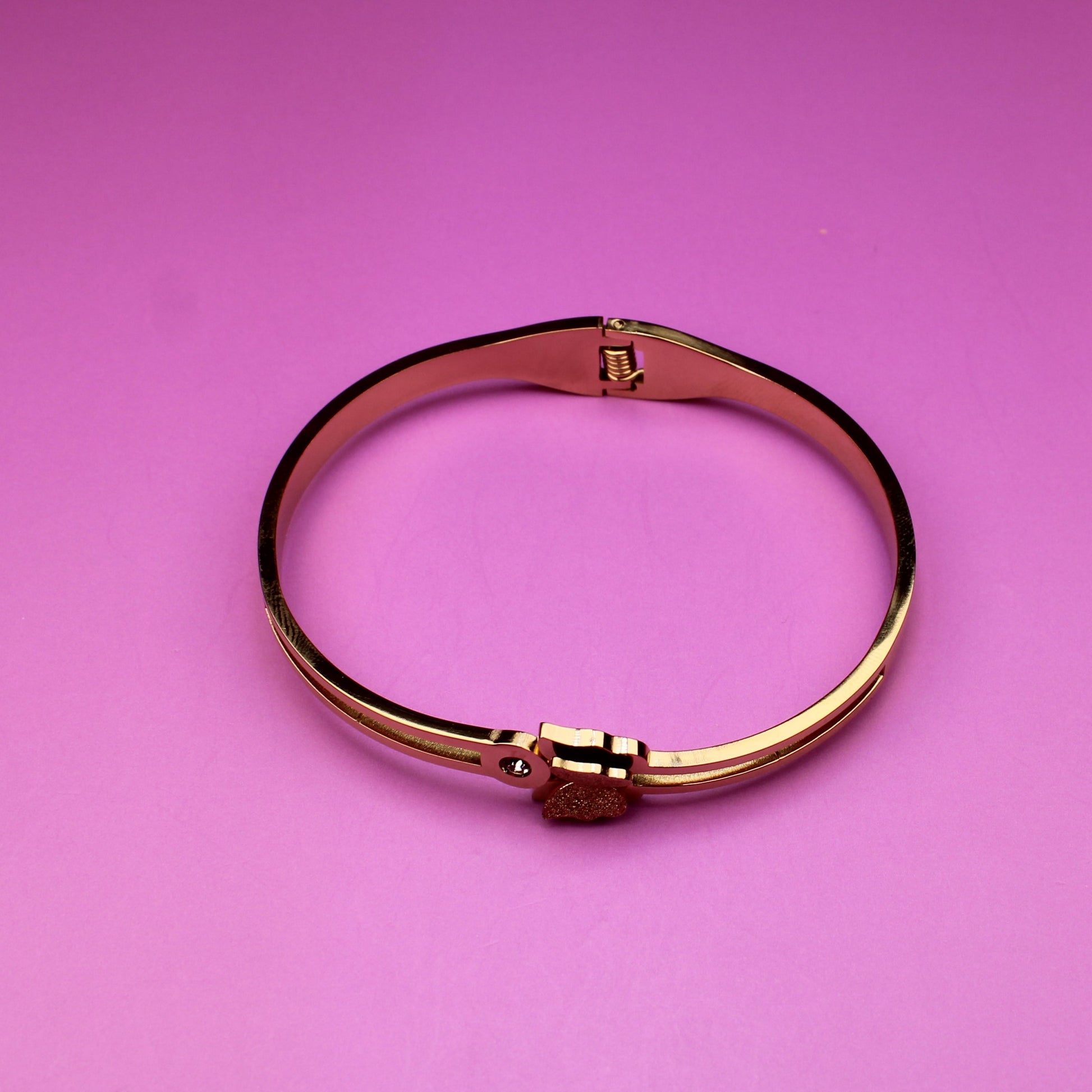 Gold bracelet on a pink background