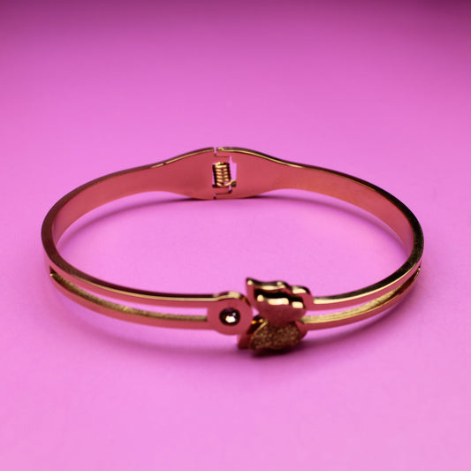 Rose gold bracelet with a heart charm on a pink background