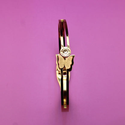 Gold ring with a butterfly design on a pink background