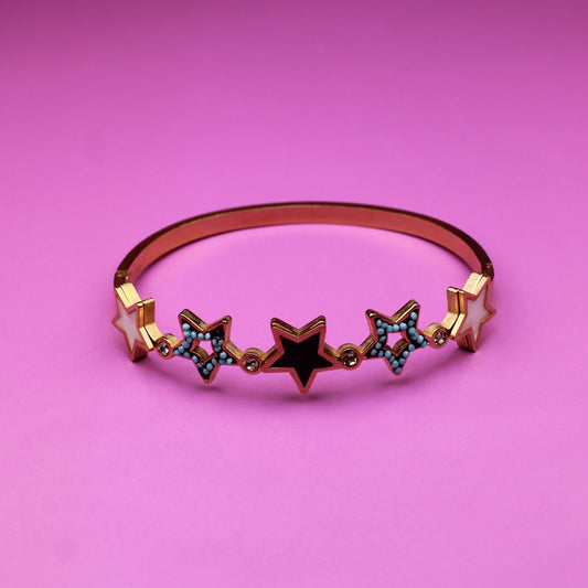 Rose gold bracelet with star-shaped charms on a pink background