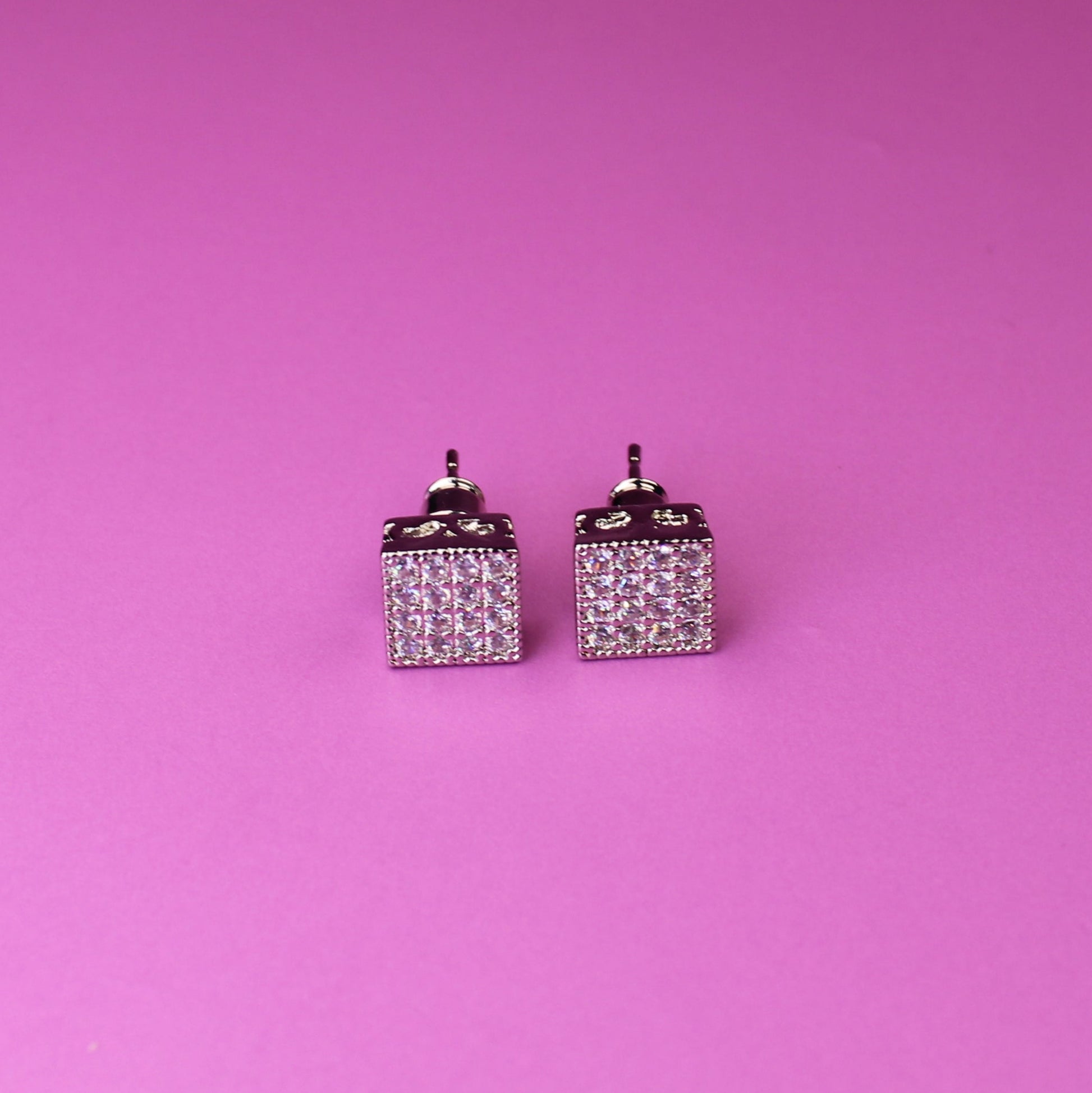 Pair of square earrings with small diamonds on a pink background