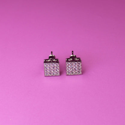 Pair of square earrings with small diamonds on a pink background