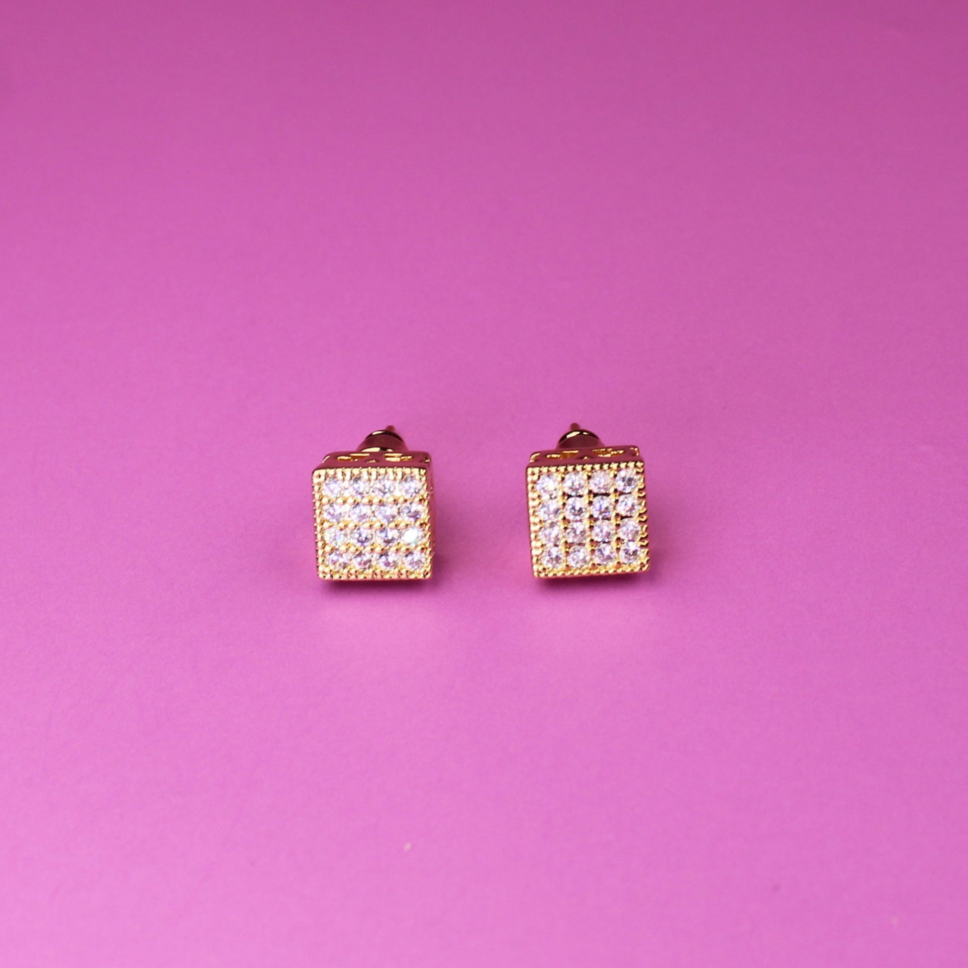 Pair of diamond-studded earrings on a pink background