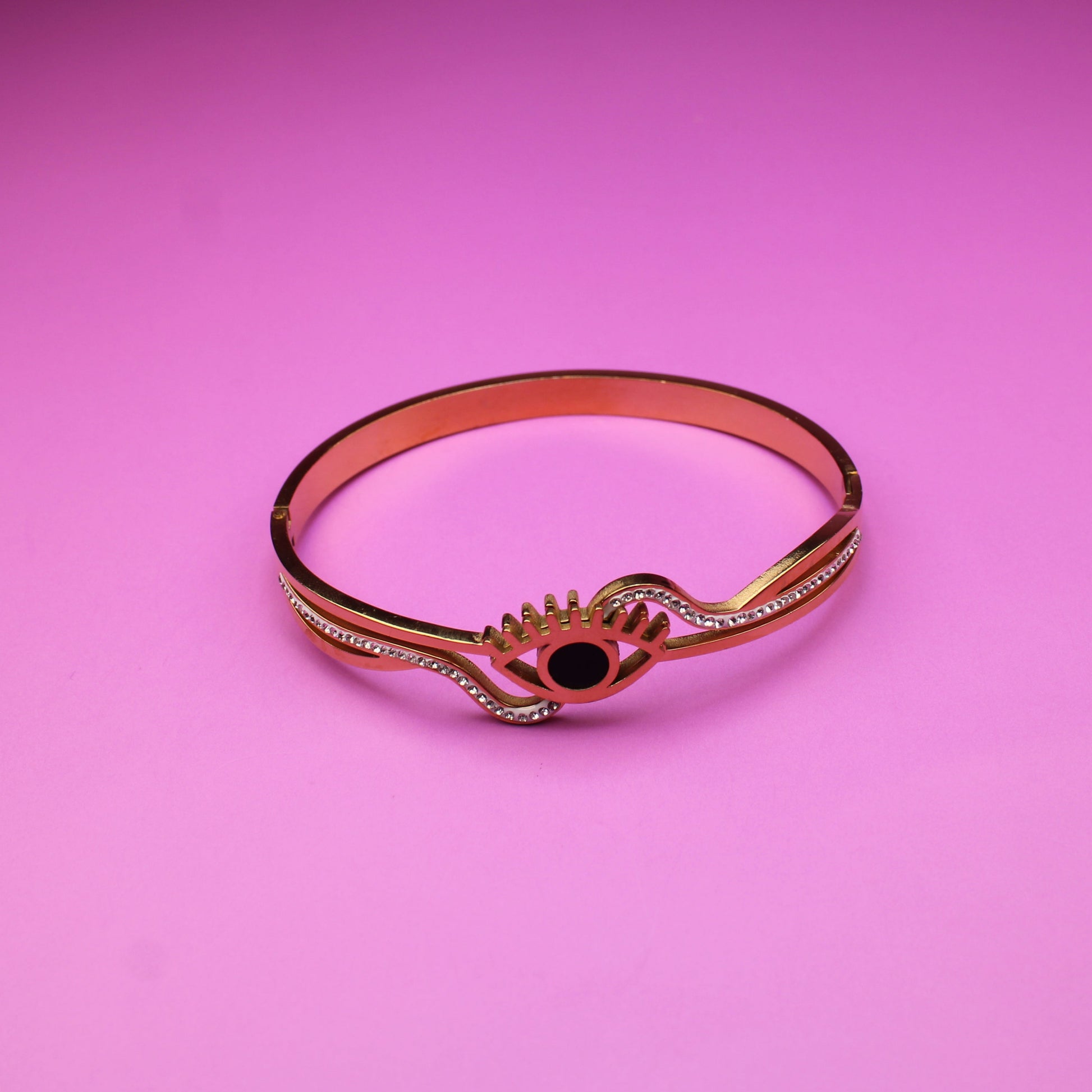 Rose gold bracelet with a black gemstone on a pink background